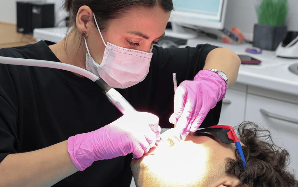 ортодонт устанавливает брекеты пациенту со скученностью зубов